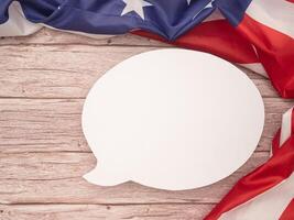 Top view of the American flag with a blank white speech bubble over a wooden table photo