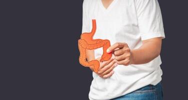 Hands holding a colon symbol and touching stomach painful suffering from stomach ache while standing on a gray background photo