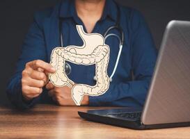 Hand of the doctor holding a colon symbol while sitting at the table in the hospital photo