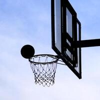 Silhouette of Basketball Hoop and Ball Against a Clear Blue Sky Capturing the Essence of Outdoor Sports and Recreation photo