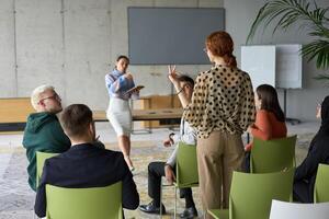A diverse group of business professionals sits attentively in a modern office, actively participating in a training session led by an instructor, focusing on the latest technological advancements in photo