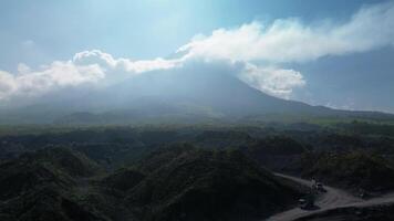 Panorama of a volcano with a barren area in the foreground with a winding road surrounded by piles of rocks and sand left over from the fall of volcanic material during an eruption video