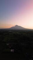 4k portrait of an active volcano in detail with a green forest in front. Portrait footage from an aerial drone shows a panorama of Mount Merapi from a distance with beautiful views in the morning video