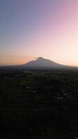 4k portrait of an active volcano in detail with a green forest in front. Portrait footage from an aerial drone shows a panorama of Mount Merapi from a distance with beautiful views in the morning video