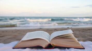 A Serene Beach Scene with a Book Lying Open on a Towel, Waves Crashing Softly in the Background video