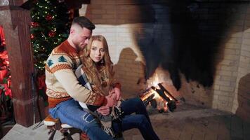 Beautiful couple in love near fireplace. Loving man and woman inside hugging in cold evening. video