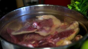 goose meat in a pot with water. chef is frying duck meat in a large pot video