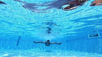 Underwater view of a happy man swimming. Man is swimming under the water in pool and showing signs ok with his hands on camera. video