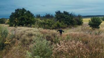 Scary figure of death in the field. Ghost in black cloak standing alone with outstretched arms by sides on nature background. video