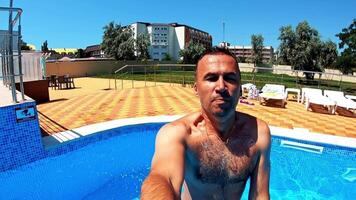 Man jumping into the swimming pool. Healthy man holding underwater camera and jumping into blue water of the pool. Summer vacation. video
