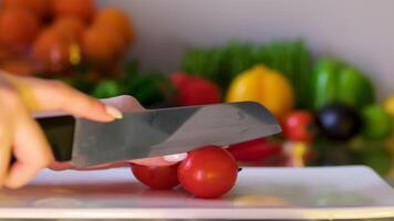 sharp chef's knife slicing tomato on cutting board close up in slow motion video
