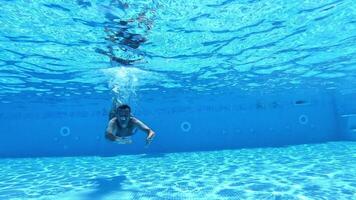 Handsome man diving into the water of the pool. Man swimming underwater in the clear water of the swimming pool. Healthy lifestyle. video