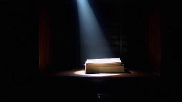 A Book Illuminated by a Single Spotlight in a Dark Room, Creating a Dramatic and Mysterious Effect video