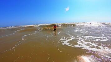 Boy enjoys in waves in the sea. Cute child jumping into big waves with white foam in a sunny summer day. Happy childhood. video
