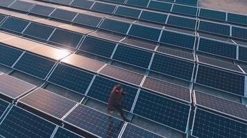 Modern solar farm on a roof at sunlight. Photographer doing photos on the background of blue solar panels. Top aerial view. video