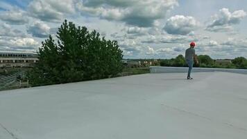 Engineer expert walking on roof. Worker in orange helmet think about new solar farm construction on rooftop of a building on nature background. Aerial view. Motion camera around. video