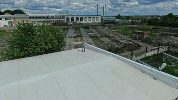 New construction of a solar farm on the field. Professional engineer standing on a rooftop of flat building and looking at the solar panels installation. Aerial view. video