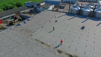 Construction os new solar farm on a roof. Panoramic view of a rooftop of industrial building with workers installing basis for future solar panels. Aerial view. video