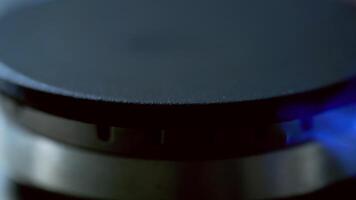Gas is switching on automatically. Blue flame appearing on a gas stove on dark background. Close-up. video