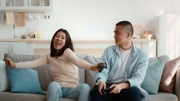 Two friends relax on a sofa in a bright living room, playing games together. They share smiles and laughter, enjoying their time in this comfortable space. video