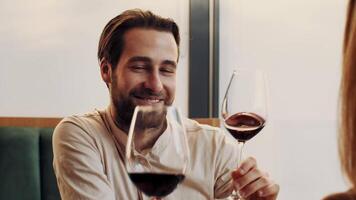 uma homem envolve dentro uma amigáveis conversação enquanto segurando uma vidro do vermelho vinho às uma contemporâneo restaurante. a configuração é relaxado, com natural luz realçando a atmosfera. video