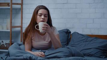 A woman sits in bed on a cold winter morning, sipping tea and lost in thought. The cozy room reflects a sense of isolation while she grapples with feelings of anxiety and depression. video
