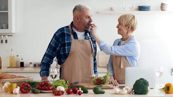 A couple is joyfully prepping a meal in their bright kitchen. They are surrounded by fresh vegetables and ingredients, showcasing teamwork and communication as they cook. video