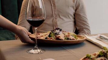 une bien habillé la personne jouit une magnifiquement plaqué gourmet plat entouré par bien du vin à une élégant restaurant tableau, création un attrayant atmosphère pour une mémorable repas. video