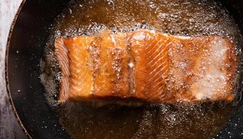 fillet of fresh salmon sizzling in bubbling oil with golden crispy textures forming during frying process photo