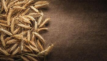top-down photo of golden wheat stalks arranged on a textured brown fabric background, perfect for rustic and agricultural themes