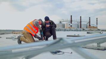 Solar technicians working on a solar farm using a drill. Workers installing photovoltaic solar panels on the roof of building, which converts solar energy into electric energy. video