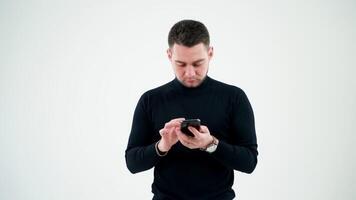Serious man touching the screen of smartphone indoors. Bearded businessman holding a modern gadget in his hands and working on it in empty studio. video