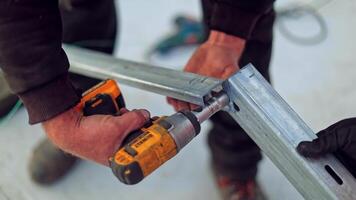 Engineers installing basis for solar panels. Worker's hands is attaching metal frame with a drill. Close-up. video