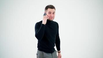 profissional criativo homem falando em a Smartphone. bonito homem dentro Preto suéter usando Móvel telefone isolado em branco estúdio fundo. video