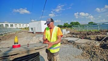 Building works on the solar farm. Male worker unwinds hose pipe on the field. Construction of solar power plant for renewable energy. video