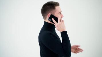 Smiling man walks and talk the phone on white background. Handsome businessman giving instructions through the mobile phone conversation. video