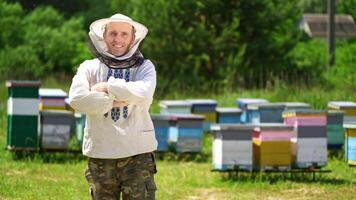 Beekeeper on a farm. Half-length portrait of male apiarist in a protective hat on the background of apiary. Production of natural product. Apiary concept. video