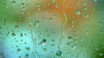 Raindrops on blur colorful background. Large drops flowing on glass window slowly in rainy weather. Close-up. video
