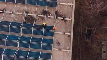 Installation of solar panels on roof. Solar technicians construct photovoltaic panels on the building. Top aerial view. Camera moving up. video