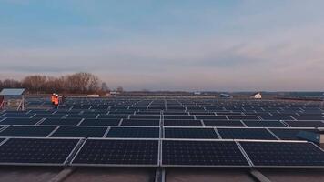 Photovoltaic solar panels on a flat roof at sunset. Solar energy farm under the evening sky. Renewable source of clean energy. video