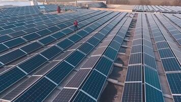 Modern solar power plant on the top of a building. Man is walking among solar cells. Alternative source of clean energy from the sun. Aerial view. video