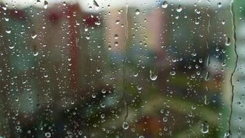 Droplets on glass during rain. Raindrops falling on the window on blur background outside. Wet weather. Close-up. video