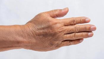 macro image of wrinkles on the back of the hand with visible veins and age spots in isolated white background photo
