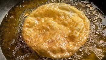 top view of crispy golden roti frying in bubbling hot oil showcasing detailed texture and frying process photo