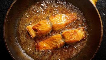 fish fillets frying in hot bubbling oil with golden brown textures forming during cooking in a skillet photo