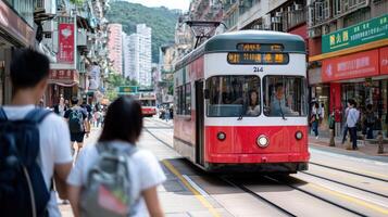 A red and white tram travels down a busy street in Hong Kong. People walk on the sidewalk. photo