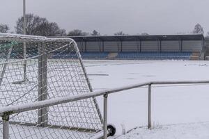 Snow covering soccer field and bleachers on overcast day photo