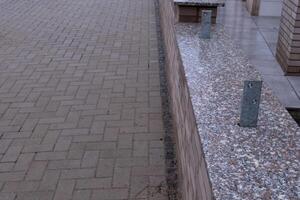 Granite slabs resting on brick wall next to cobblestone pavement photo