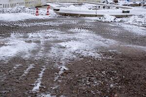 Melting snow leaving puddles in construction site during winter photo