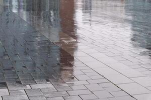 Wet pavement reflecting buildings on a rainy day photo